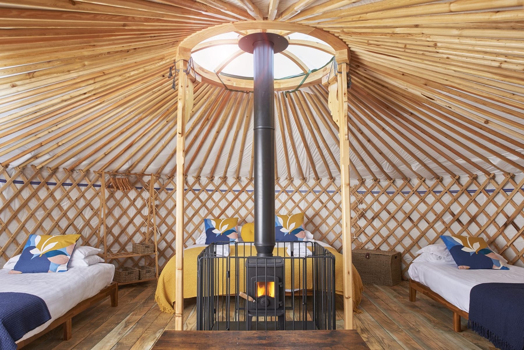 Inside Budhyn yurt, wood burner beneath the crown skylight with a super-king and two single beds