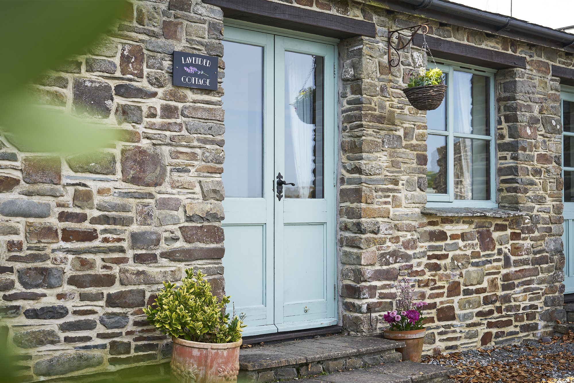 Lavender Cottage exterior — stone cottage with the Lavender Cottage sign at Woodlands Manor Farm, Bude