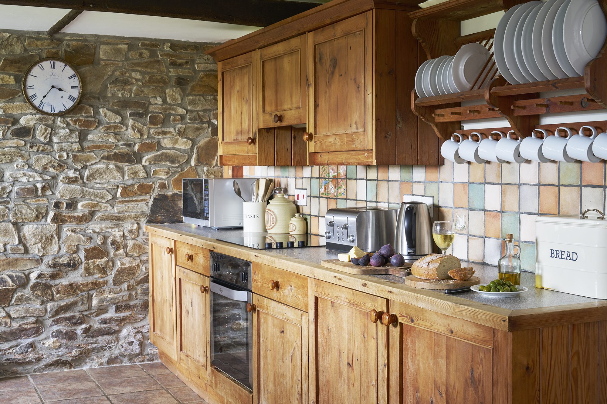 Rose Cottage kitchen with wooden units against the stone wall