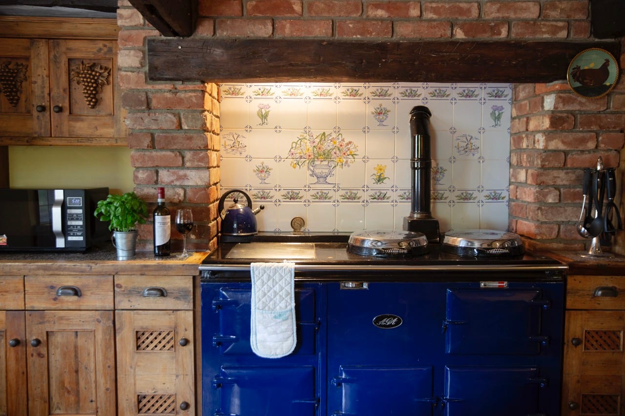 The four-oven blue AGA range set in the brick chimney breast