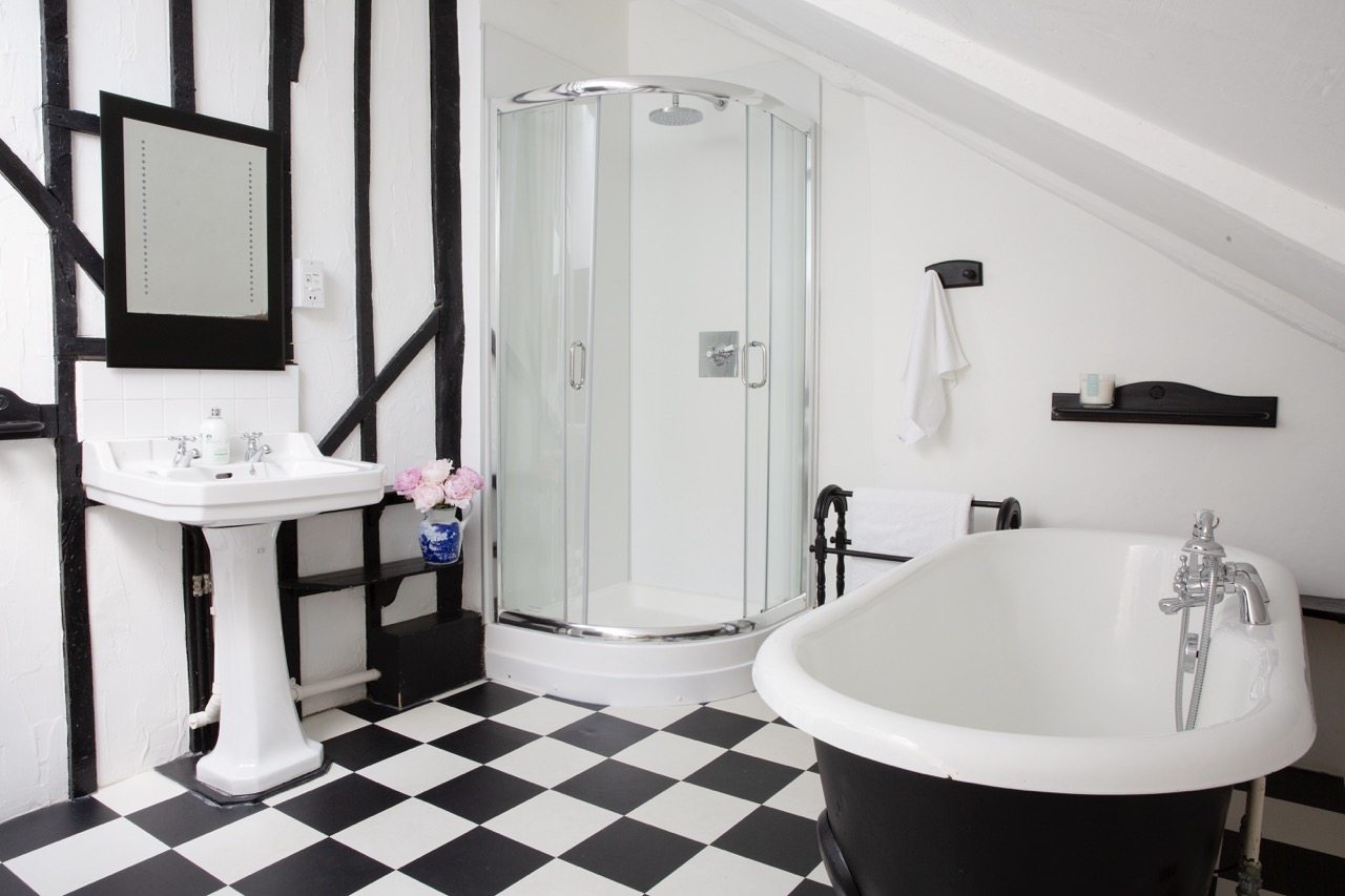 Manor House bathroom with black roll-top bath and beamed walls